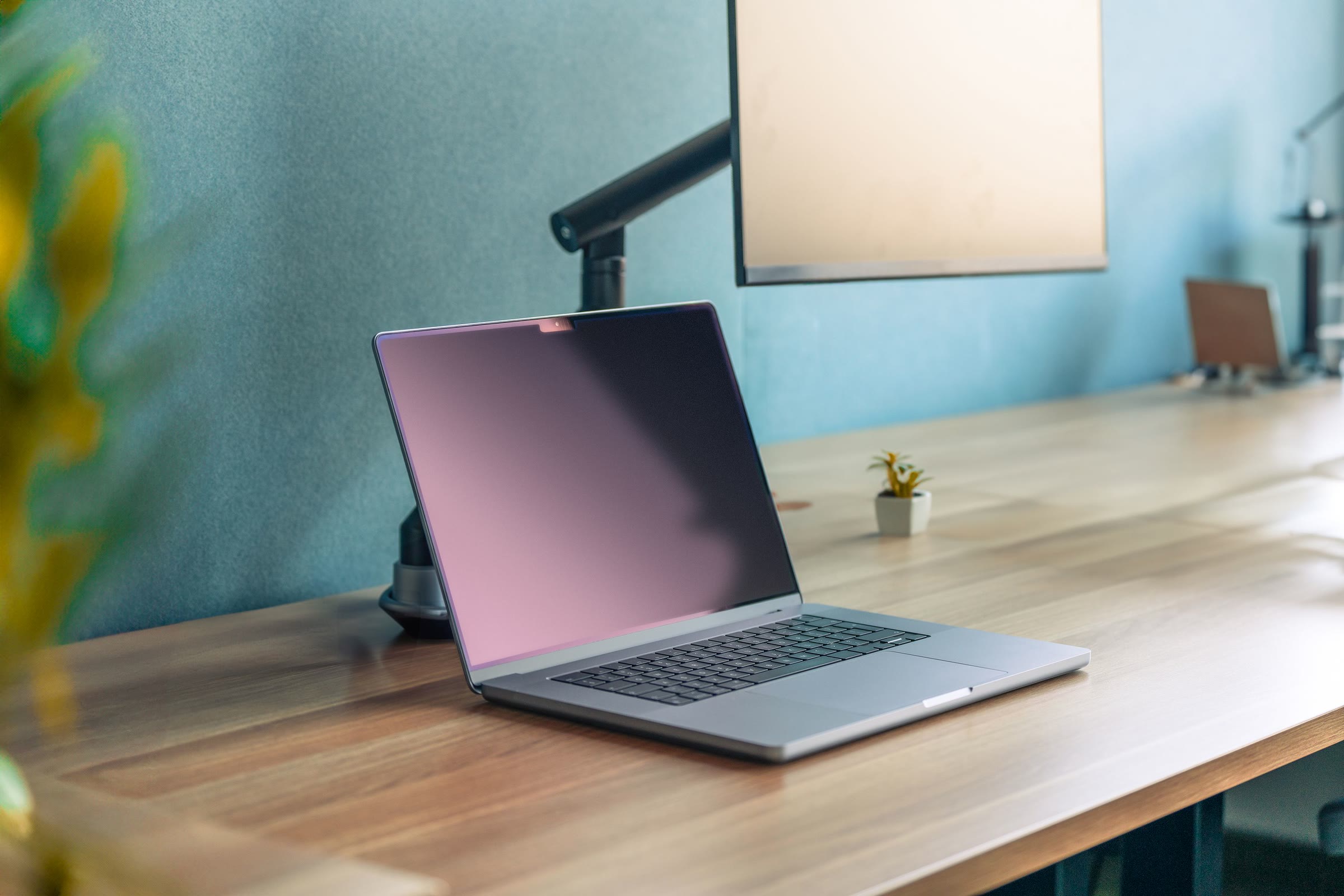 Un ordinateur portable ouvert sur un bureau en bois, à la lumière du jour