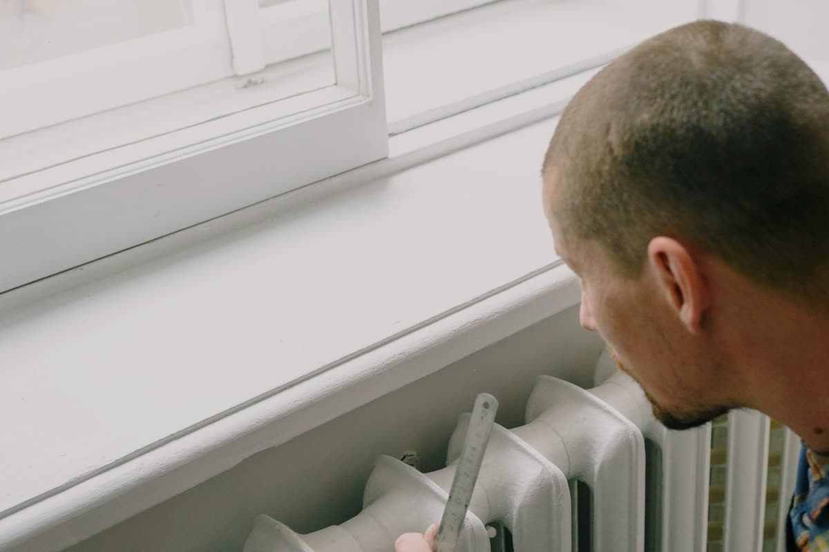 Artisan mesurant un radiateur avant son remplacement