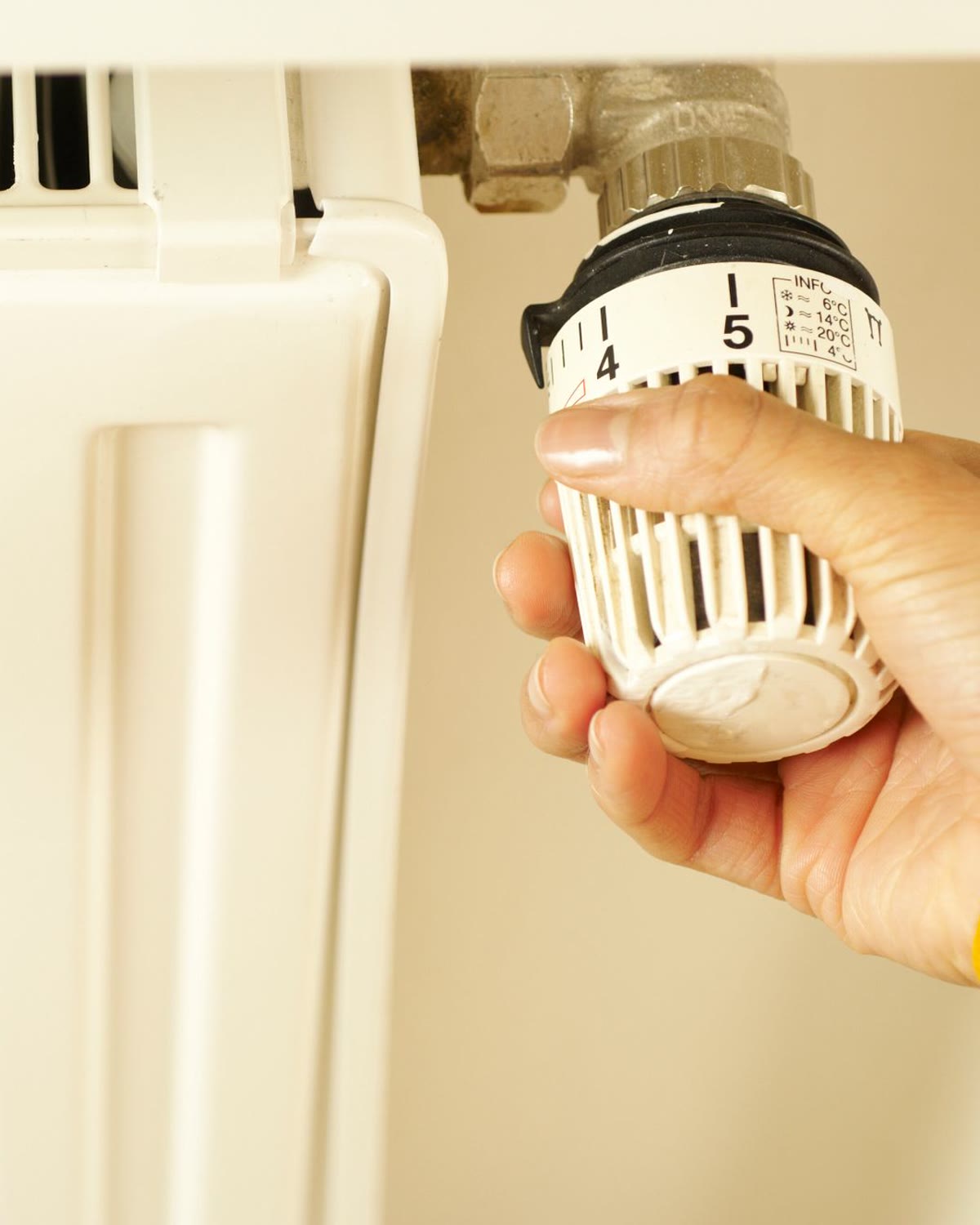 Main réglant la tête thermostatique d'un radiateur